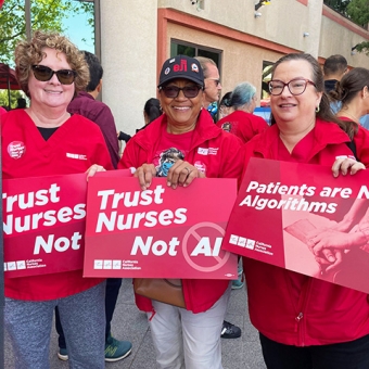 Three nurses hold signs "Trust Nurses, Not A.I."