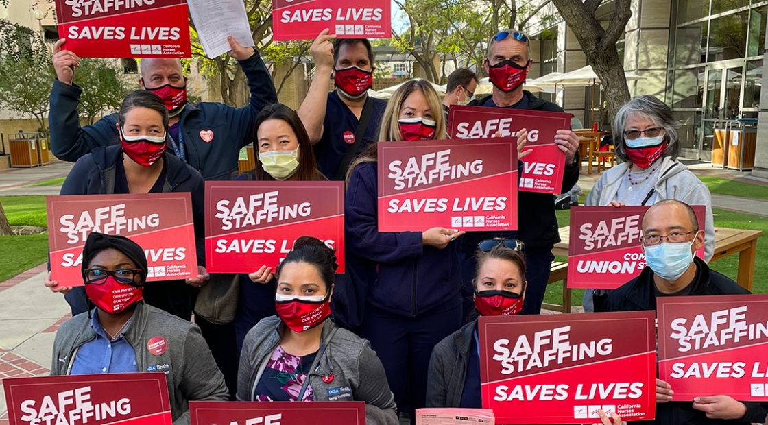 Large group of nurses holding signs "Safe Staffing Saves Lives"