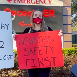 Nurse holds sign "Newborn Safety First"