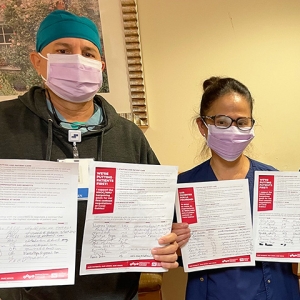 Three nursews inside hospital hold papers with signatures