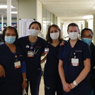 Group of five nurses arm-in-arm in hospital hallway
