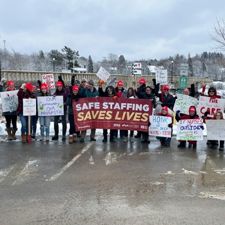 Large group of Machias nurses outside holding banner "Safe Staffing Saves Lives"