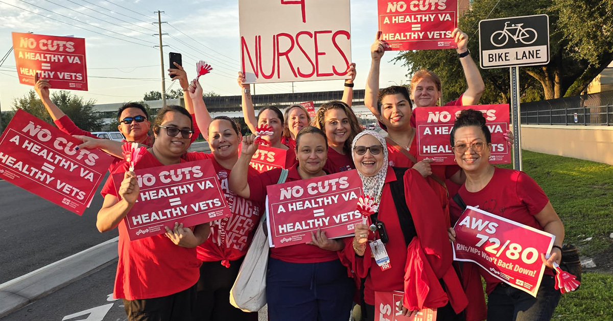 Group of nurses by side of the road smiling, holding signs "No Cuts: A Healthy VA = Healthy Vets"