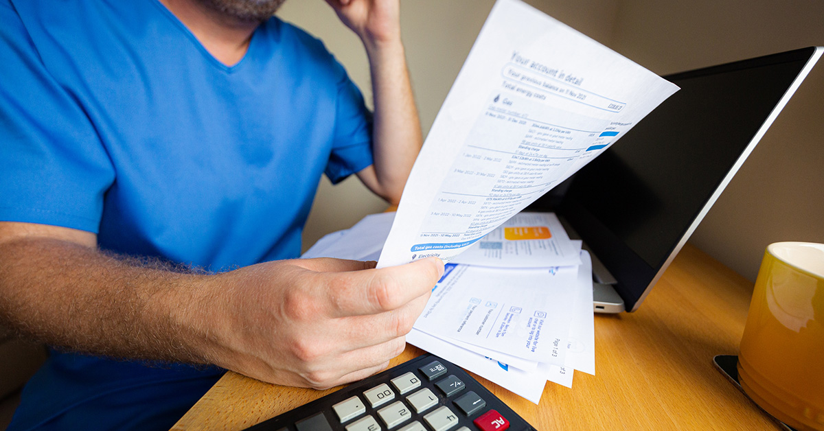 Nurse holding papers in front of computer and calculator