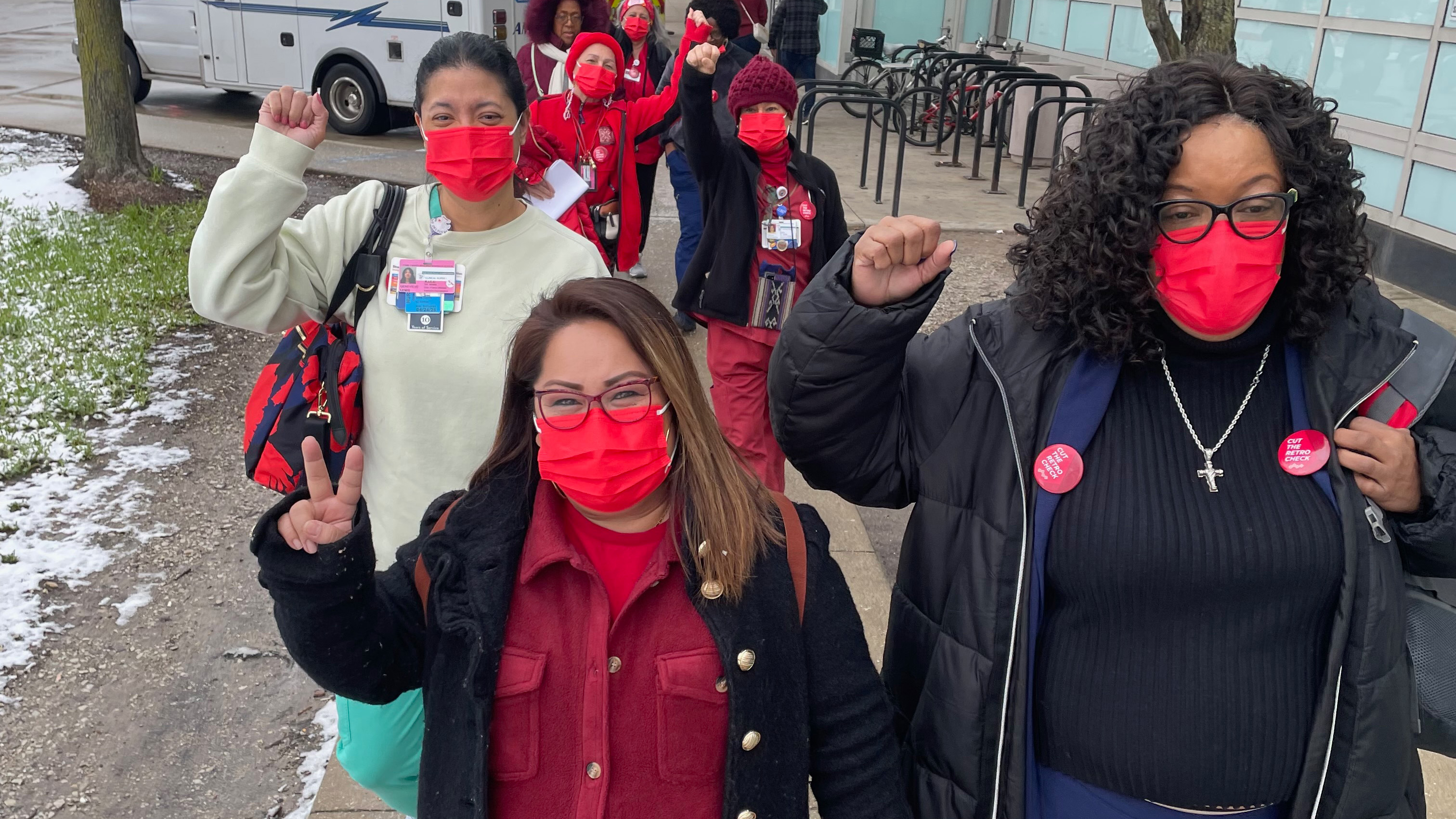 Nurses walking outside hospital with raised fists