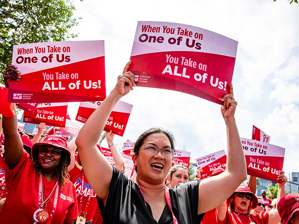 Nurses marching holding signs "When you take on one of us, you take on all of us!"