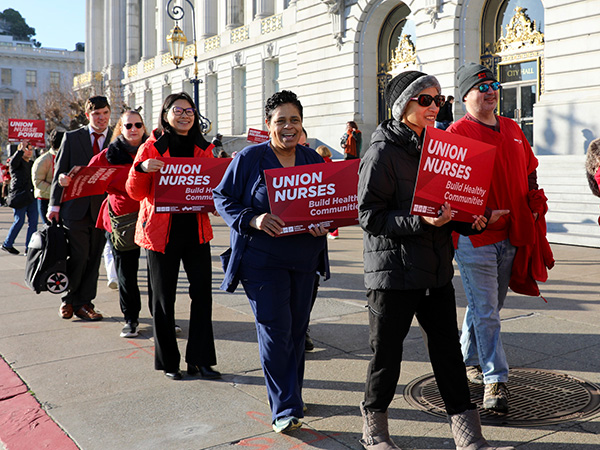 Nurses marching holding signs "Union Nurses Build Healthy Communities"