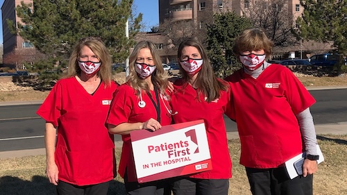 Group of four nurses outside hospital hold sign "Patients First"