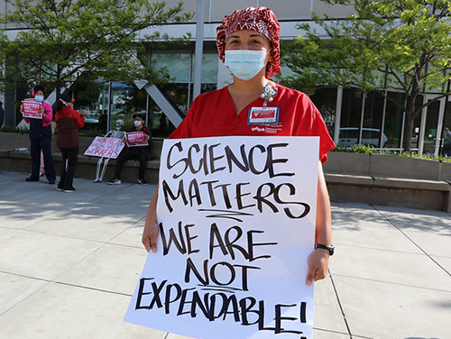 Nurse holds sign "Science Matters. We Are Not Expendable"