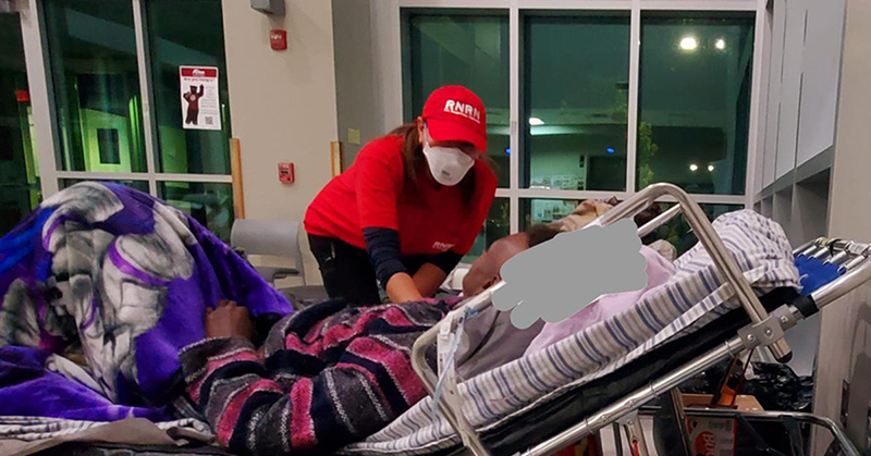 Nurse in RNRN hat tending to patietn in hospital bed