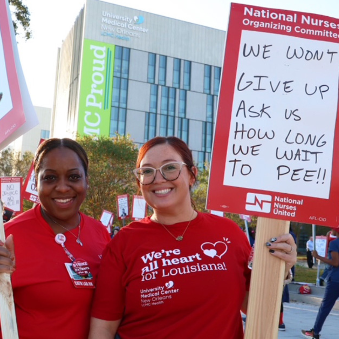 Two UMC nurses in red hold picket sign outside their hospital.