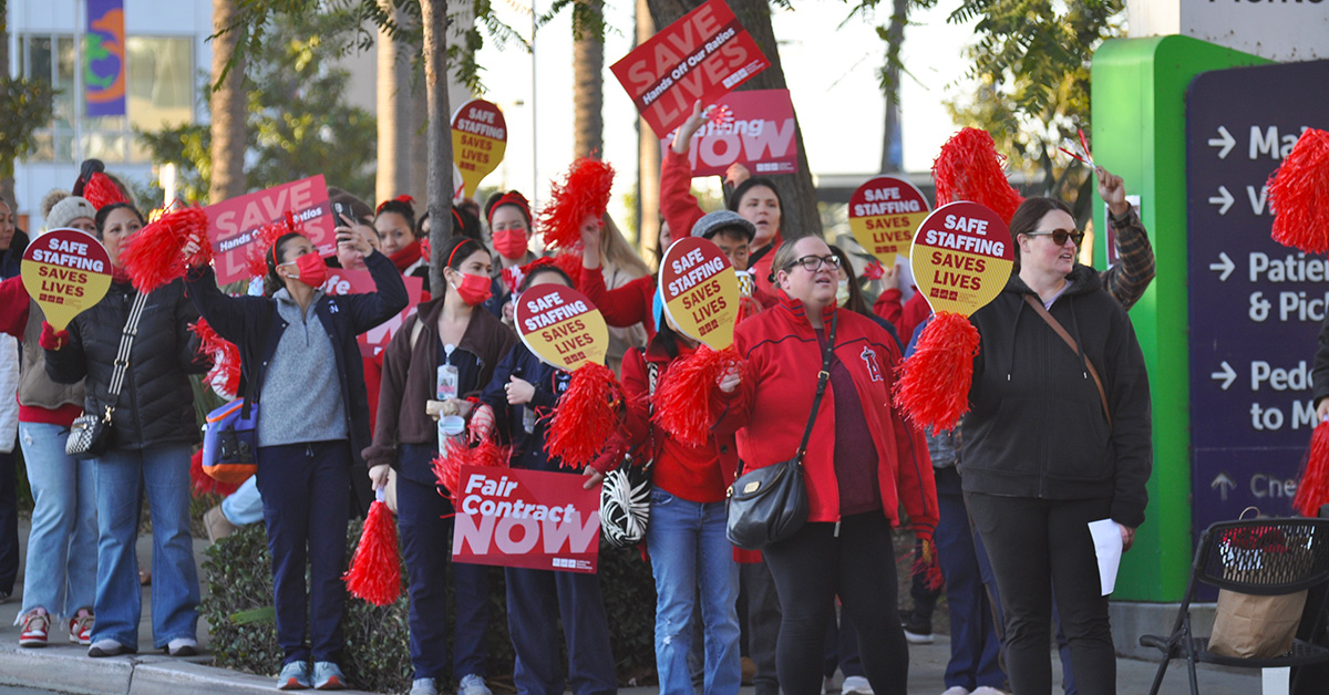 Nurses on picket line holding signs for safe staffing.