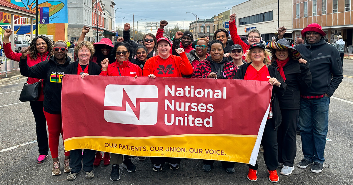 Nurses with raised fists, smiling, and hold banner "Nationall Nurses United"