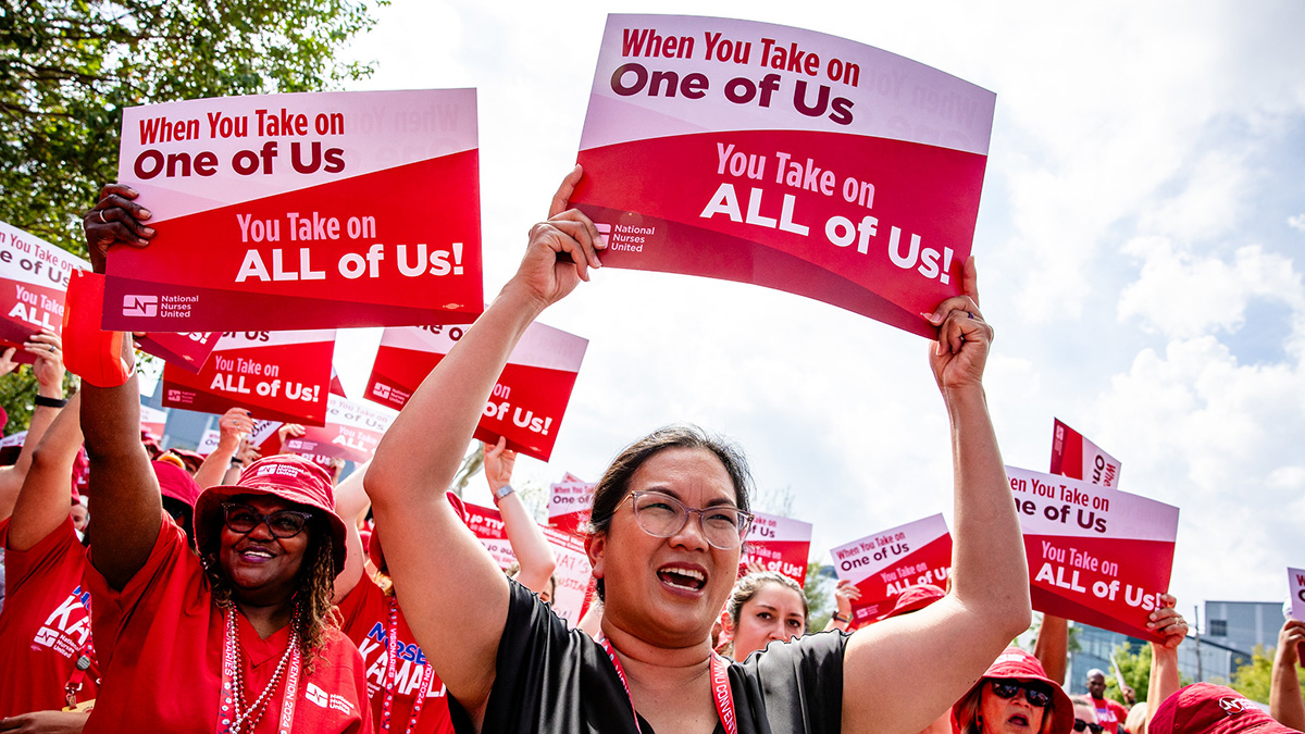 Nurse outside holding signs "When you take on one of us, you take on all of us!"