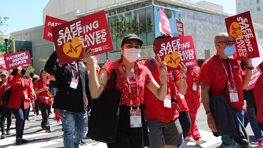 Nurses marching holding signs "Safe Staffing Saves Lives"