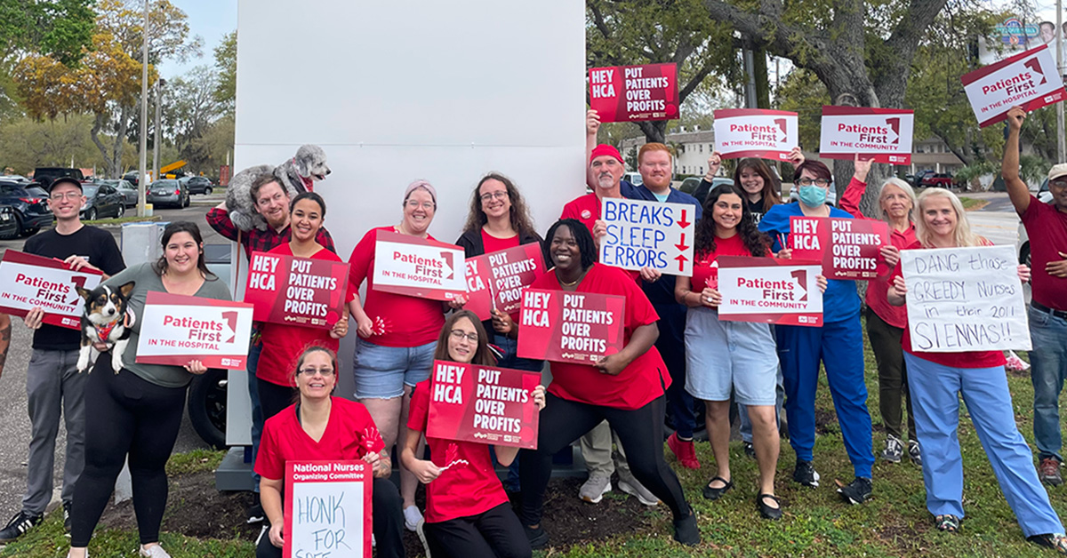 Large group of nurses outside HCA Florida Largo Hospital holding signs "Hey HCA Put Patients Over Profits" and more.