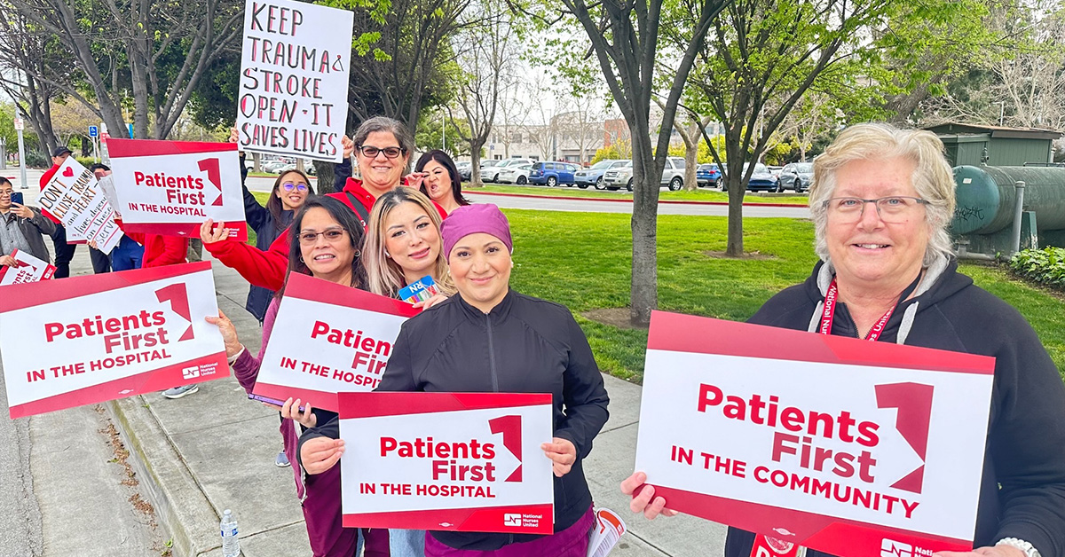 Nurses outside holding signs "Patients First in the Community"