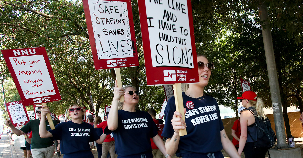 Three nurses on picket line wearing shirts "Safe Staffing Saves Lives"