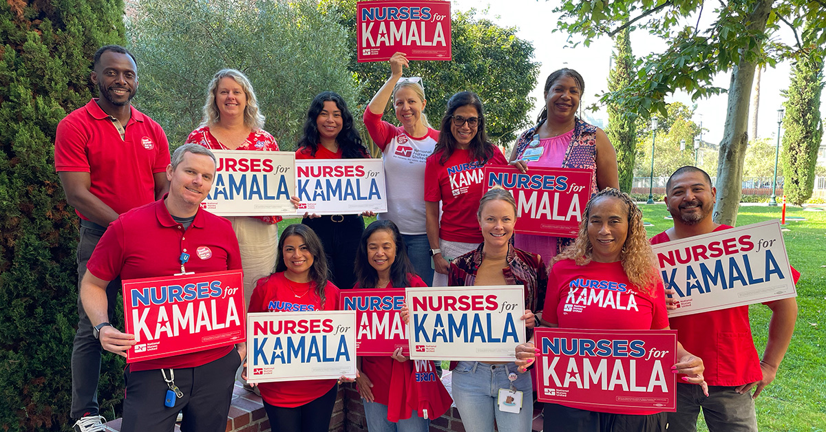 Group of nurses holding red and white "Nurses for Kamala" signs