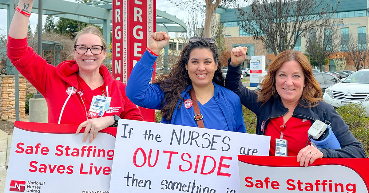 Three nureses outside of hospital, smiling, fists raised, and holding signs "Safe Staffing Saves Lives"