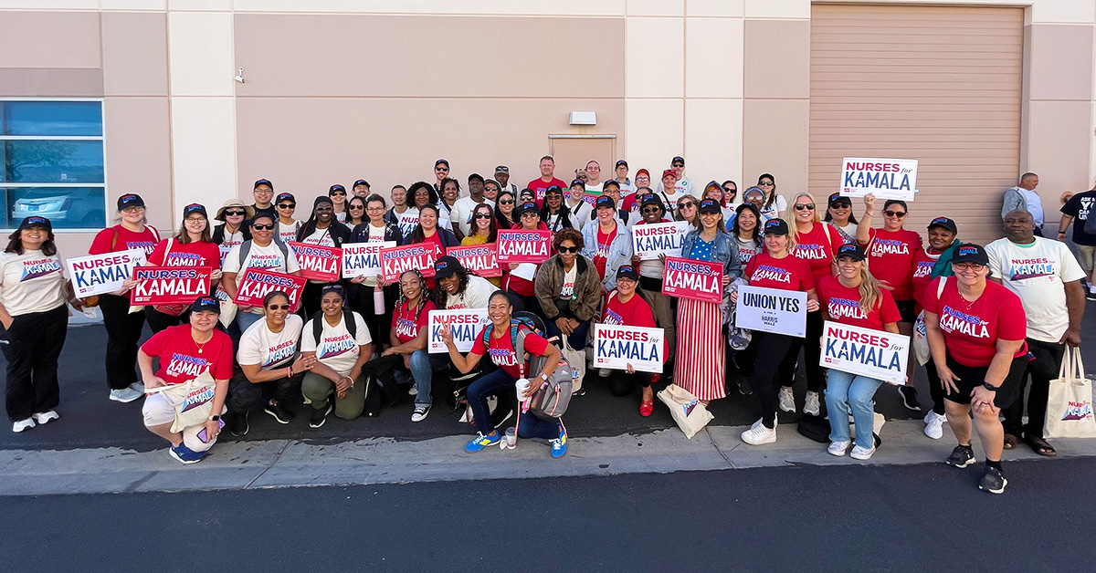 Large group of nurses outside, smiling, with canvassing materials and shirts "Nurses for Kamala"