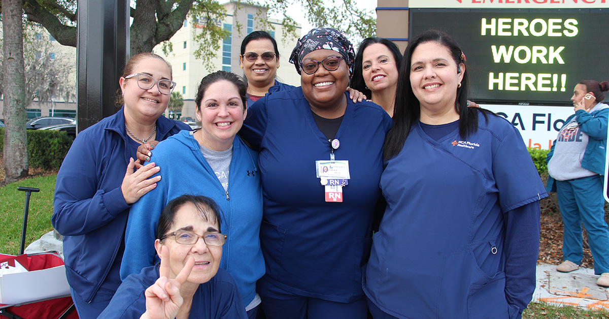 Group of nurses in blue scrubs standing together and smiling