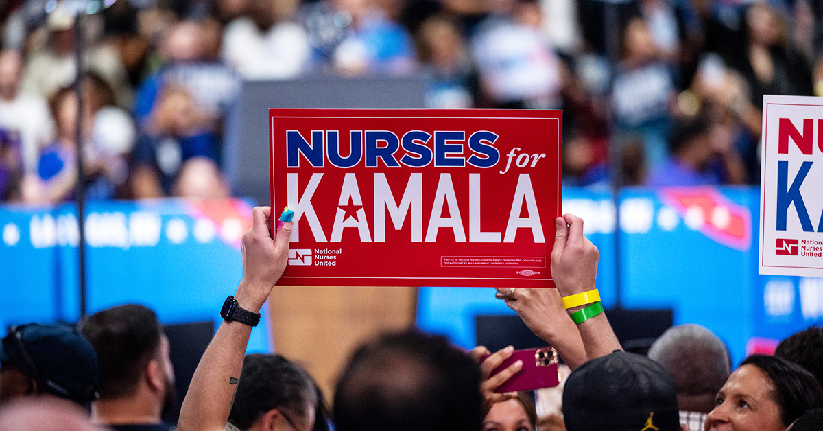 Arms holding sign "Nurses for Kamala"