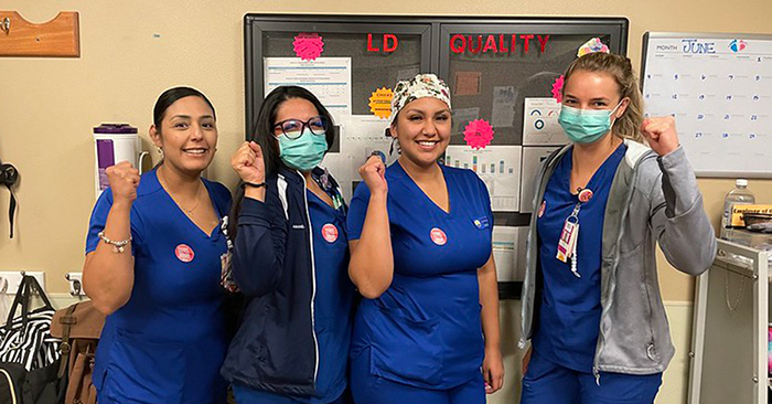 Four nurses inside hospital giving thumbs up