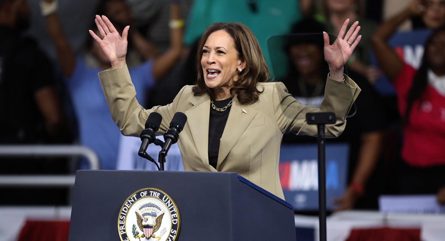 Vice President Kamala Harris speaking into microphone at indoor rally