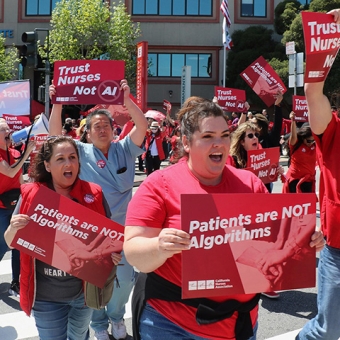 Nurses marching holding signs "Trust Nurses, Not AI" and "Patients Are Not Algorithms"