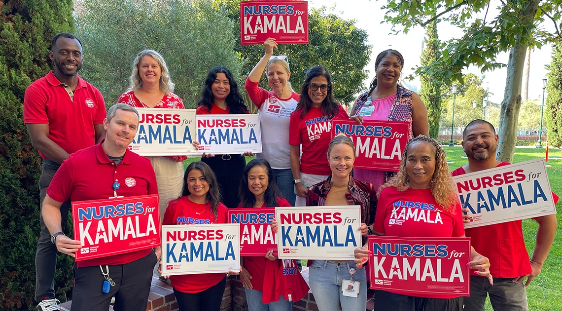 Group of nurses holding red and white "Nurses for Kamala" signs