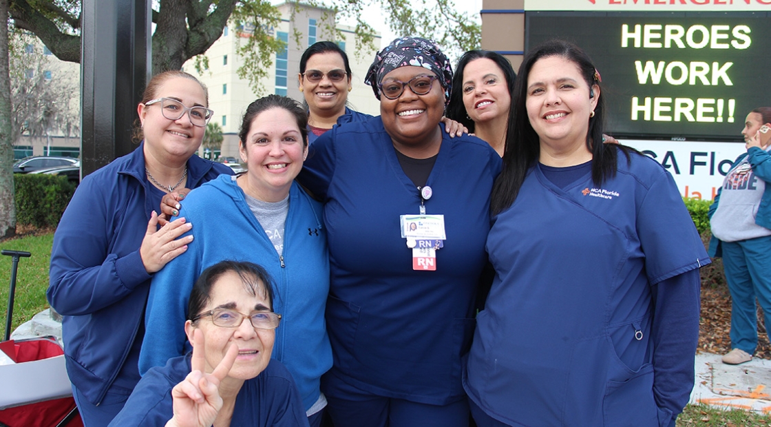 Group of nurses in blue scrubs standing together and smiling