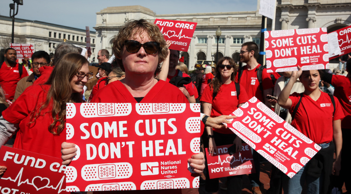 Nurses holding signs "Some Cuts Don't Heal"