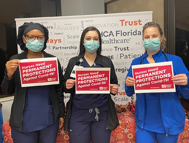 Three nurses holding signs "Nurses Need Permament Protections Against Covid-19"
