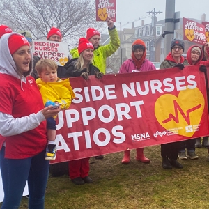 Group of nurses standing outside in cold weather holding banner "Bedside Nurses Support Ratios"