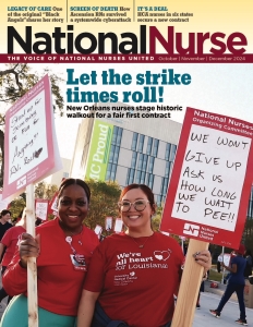 Two nurses outside hospital smiling and holding signs, "Stand up for something or fall for anything" and "We won't give up"