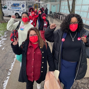 Nurses walking outside hospital with raised fists