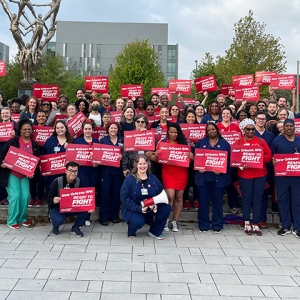 Large group of nurses outside hospital holding signs "New Orleans RNs:Ready to Fight"