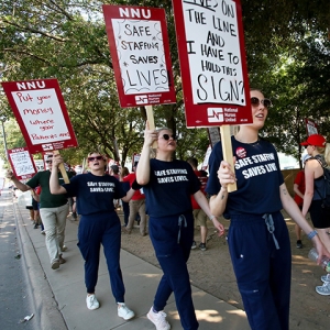 Three nurses on picket line wearing shirts "Safe Staffing Saves Lives"