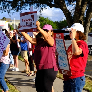 Nurses on picket line, one holds signs "Patients First in the Hospital"