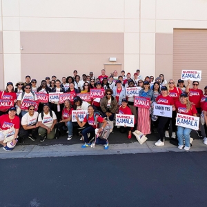 Large group of nurses outside, smiling, with canvassing materials and shirts "Nurses for Kamala"