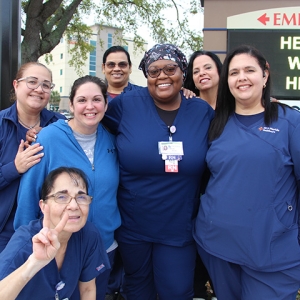 Group of nurses in blue scrubs standing together and smiling