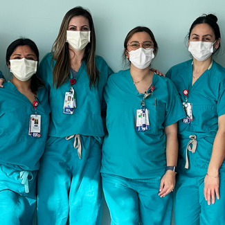 Four nurses in scrubs posing for picture side by side
