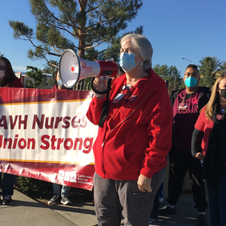 AVH RN speaks using megaphone in front of sign "AVH Nurses - Union Strong"