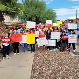 Large group of nurses outside hospital holding signs calling for safe staffing