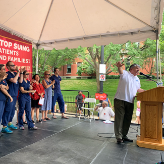 Richard Trumka speaking at outdoor podium in front of nurses