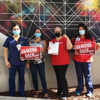 Davis nurses outside holding signs "UC Nurses Demand Safe Staffing"