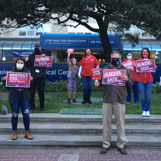 Nurses outside UCSF hospital hold signs calling for safe staffing