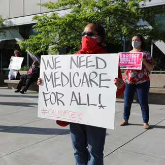 Nurse holds sign "We need Medicare for All"